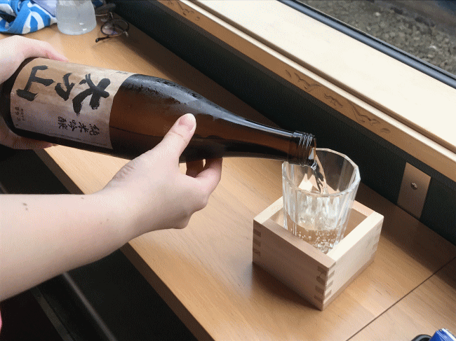 べるもんたのアテンダントさんが日本酒を注ぐ